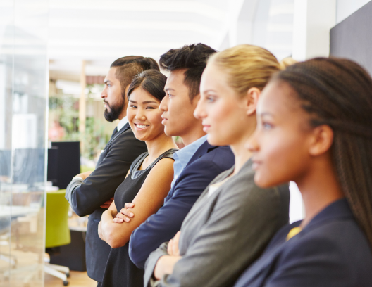 employees standing in a line looking in the same direction with one smiling at the camera