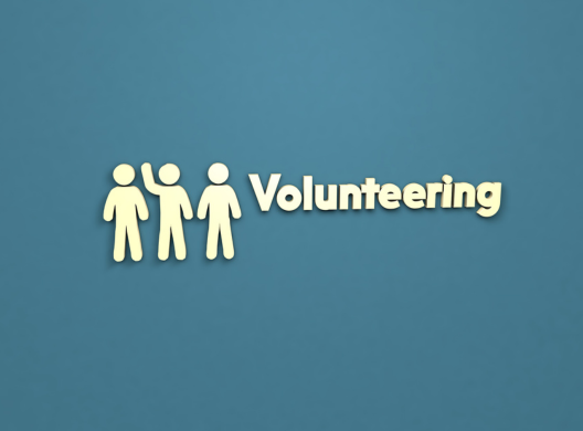 The word Volunteering next to a cartoon image of three people with one of them waving.