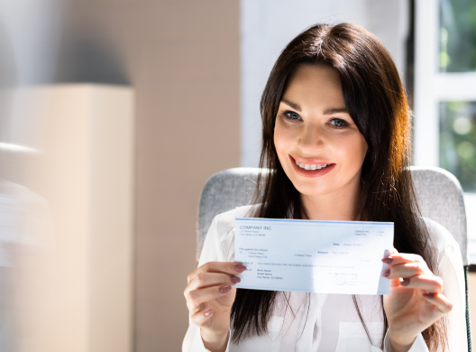 young woman holding paycheck and smiling