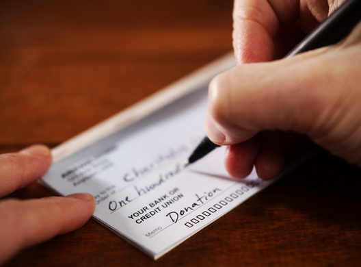 writing a paper check for donation